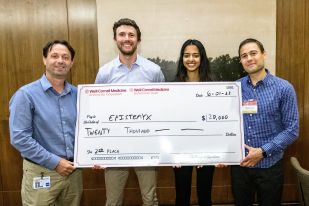 Three men and a woman holding a big check for their cash prize of $20,000